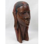 A well carved wooden bust of an African tribesman having stretched ears and red headpiece,