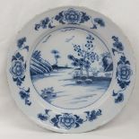 A 19thC Delft Charger hand painted with landscape and flower head decoration, 34cm diameter.