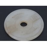 A circular carved Oriental flat disc of celadon jade, 5.5cm dia.