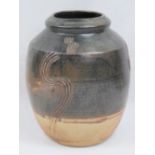 A 20thC stoneware studio vase with combed swirling designs, signed JB, 23cm high.