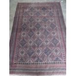 A good vintage hand woven woollen rug having multiple geometric panels upon a red ground,