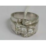 A heavy white metal and diamond ring of abstract form having central row of three square cut