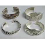 A silver Peruvian bangle having Aztec style panels a/f. Together with three white metal bangles.