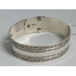 A Sterling silver bangle having two double rows of scrollwork carving and belt buckle style clasp,