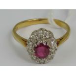 An 18ct gold ruby and diamond cluster ring, central oval cut ruby approx 0.