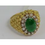 An 18ct gold green jade and diamond ring having unusual beaded yellow metal head with central jade