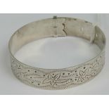 A HM silver bangle having leaf engraving throughout and belt buckle style clasp, 6.4cm max dia, 5.