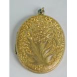 A large oval yellow metal locket having floral bouquet engraving to front and ivy and shield