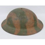 A WWI American Brodie helmet with original camo paint and having name marked upon.