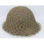 A WWII Japanese Infantry issue helmet with scrim netting and regimental brass badge upon,