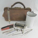 A leather doctors bag opening to reveal a quantity of vintage medical equipment within,