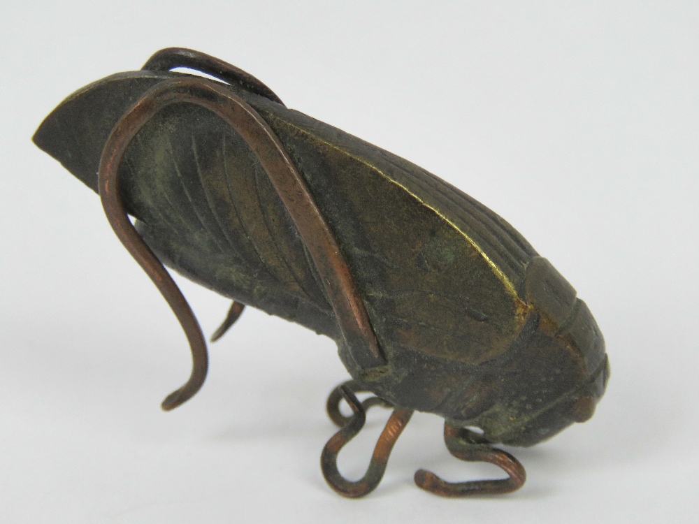 A bronze locust complete with six legs w