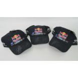 Three Red Bull Racing caps signed by Sebastian Vettel (x3) and Mark Webber (x2).