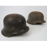 Two WWII German Infantry helmet shells; one having remains of a decal, liner band and chinstrap.