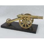 A miniature brass cannon raised over ebonised base, total length 28cm.