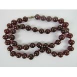 A vintage 'cherry' amber necklace of individually knotted beads on a silk cord, 83cm in length,