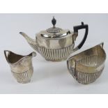 A HM silver teaset comprising teapot with gadrooned body and ebonised wooden handle,