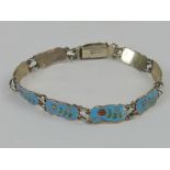 A sterling silver and enamel bracelet having nine blue ground floral panels, 16cm in length.