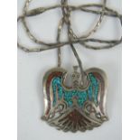 A white metal pendant in the Native American style set with turquoise chips and complete with