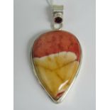 A large hardstone pendant in reds and yellows, white metal teardrop shaped mount,