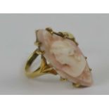 A 14ct gold and 'angel skin' coral cameo ring, the coral carved with a Classical female bust upon,