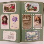 An Art Nouveau postcard album (binding a/f) containing a quantity of early 20th century vintage