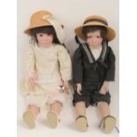 A pair of contemporary porcelain dolls each having glass eyes and vintage attire,