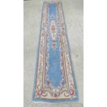 A blue ground woolen and silk runner with floral decoration, 310 x 70cm, slightly a/f.