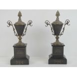 A pair of Victorian slate clock garnitures in the form of brass and slate trophies raised over