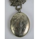A large oval HM silver locket having daffodil engraving to front, measuring 6cm including bale,