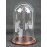 A contemporary glass dome having wooden base, dome 14cm dia, overall height 27.5cm.