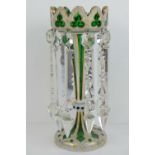 A Victorian green glass lustre embellished with gilt painted foliate designs on a white painted