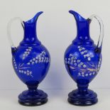 A pair of Bohemian cobalt blue glass jugs each having clear glass handle and hand painted floral