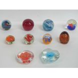 Ten art glass paperweights in blues and reds.