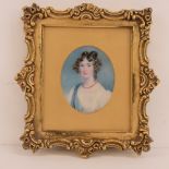 A miniature on ivory depicting an early 19th century lady in ringlets and coral necklace,
