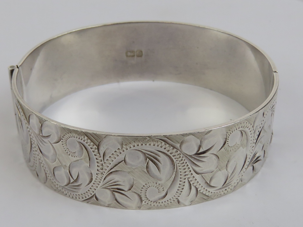 A HM silver bangle having engraved vine and leaf pattern to front, hallmarked Birmingham 1975.