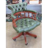 A 'Captains' chair having button back and seat in green leather, raised over plastic casters.