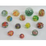 Fourteen art glass paperweights in yellows and greens.