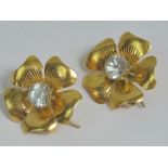 A pair of floral earrings each having five petals and central claw set moissanite, each approx 0.