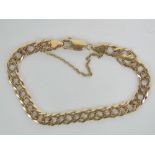 A 9ct gold double flattened curb link bracelet complete with safety chain, stamped 375, 12.7g.