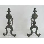 A pair of vintage cast metal fire dogs having floral motif upon, each standing 38cm high.
