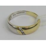 A 9ct white and yellow gold band set with a row of three round cut diamonds, hallmarked 375, size O,