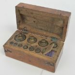 A mahogany lidded box opening to reveal a complete set of ten graduating brass weights,