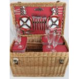 A wicker picnic basket complete with plates, cutlery and champagne glasses,