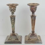 A pair of single silver plated candlesticks having square shaped stepped bases and profusely