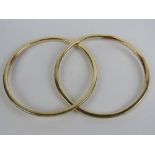 A pair of interlocked yellow metal bangles, tested as 9ct gold, 51.7g.