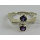 A HM silver and amethyst ring of abstract form having squared band with round cut rubover set