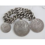 A heavy silver curb link bracelet (worn hallmarks) having three full silver coins upon.