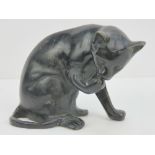 A cast brass figure of a black cat cleaning itself. 11cm high.