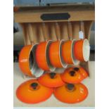 A vintage Le Creuset set of five graduated saucepans in orange complete with lids and rack bearing